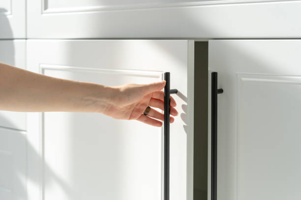 Woman's hand holding on handle of kitchen cabinet Side view of woman's hand opening white wood cupboard door by black handle. Modern kitchen furniture concept. Cozy apartment details. Closet usage handle stock pictures, royalty-free photos & images