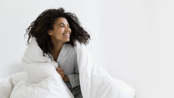 istock Happy mixed race woman covered in blanket 1359544364