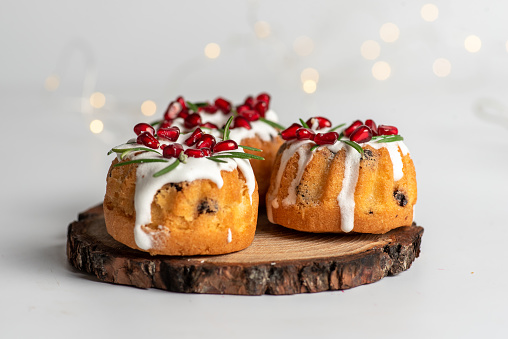 Christmas cake .Christmas mini bundt cake with sugar glaze and fruit served in a wooden plate, with Christmas decoration on a white background isolated .Stock photo.