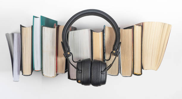 os livros de áudio se acumulam com fones de ouvido, vista superior. conceito de leitura de audiolivros - hardcover book audio - fotografias e filmes do acervo