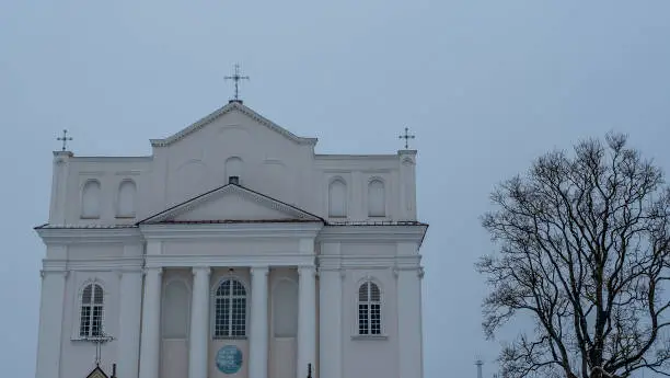 The Church of saints Cosmas and Damian in Ostrovets Grodno region with branch of tree on grey sky background. Worhsip and historical heritage concepts.