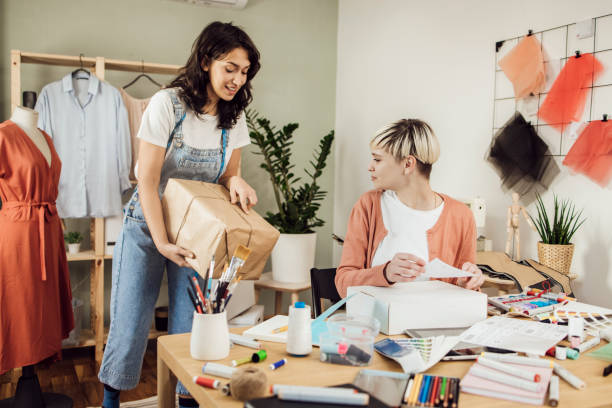 istock Two young tailors sending packages with clothing they've made for customers 1359546961