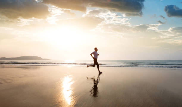 istock Man jogging on the beach at sunset 1359549737