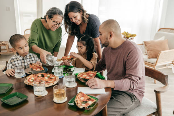 multiethnische familie mit pizza zum mittagessen - multi generation family stock-fotos und bilder