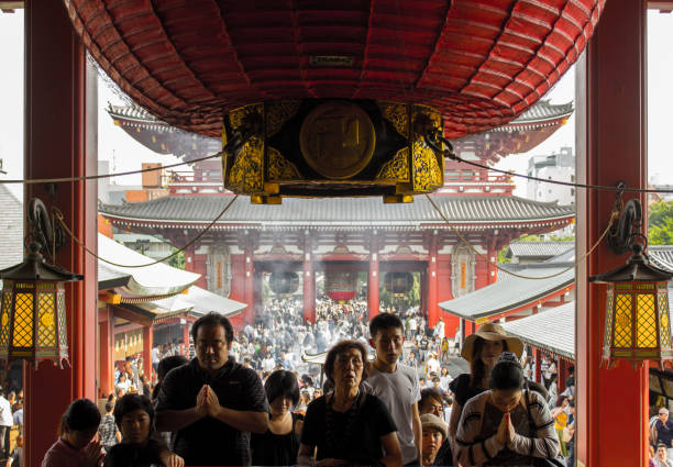 Tokyo, Japan - august 22 2019: Devote family praying at the Senso-ji buddhist temple