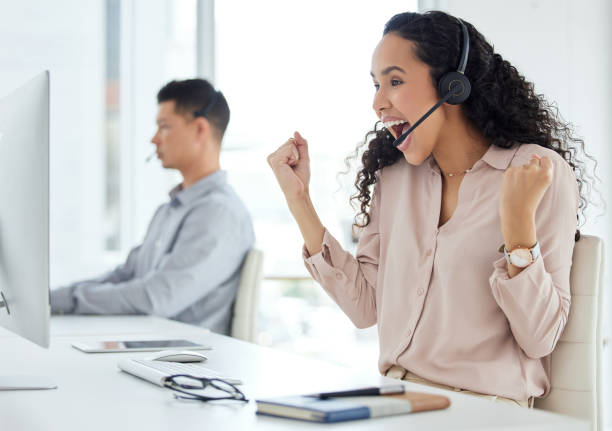 istock Shot of a young call centre agent cheering while working on a computer in an office with her colleague in the background 1359557263