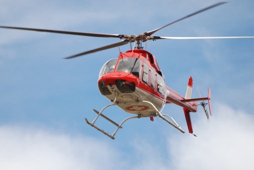 Red and white emergency medical helicopter in flight.