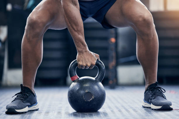 nahaufnahme eines unkenntlichen mannes, der mit einer kettlebell in einem fitnessstudio trainiert - kugelhantel stock-fotos und bilder