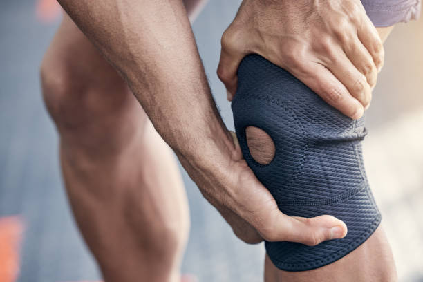 Closeup shot of an unrecognisable man holding his knee in pain while exercising in a gym Doing a lot of high-stress exercises can hurt your knee kneepad stock pictures, royalty-free photos & images