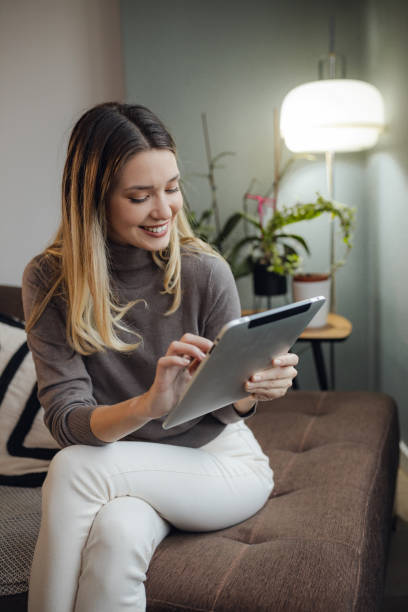 istock Beautiful woman uses a digital tablet at home 1359560942