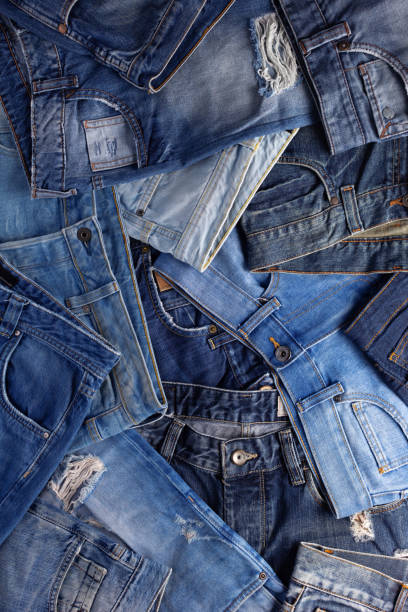 istock Stack of blue jeans denim. Jeans heap with wood background texture 1359561027
