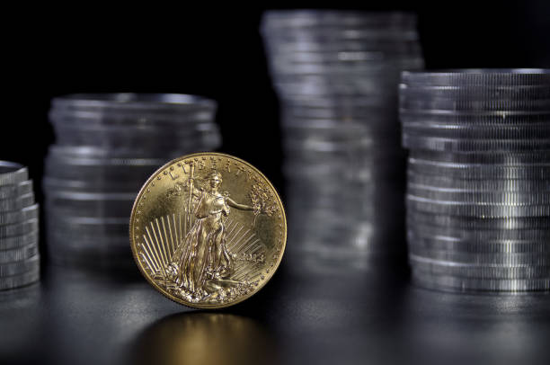 1 ounce gold coin infront of stacks of silver coins A one ounce gold coin in front stacks of 1 ounce American silver Eagle coins coin collection stock pictures, royalty-free photos & images