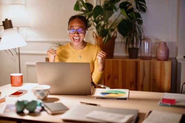 istock Attractive young businesswoman cheering while working on a laptop at night 1359563402