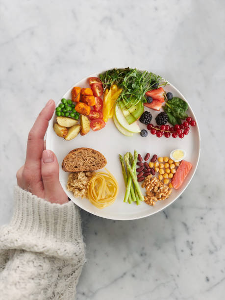 istock hand holding a dish of balanced colorful fruits and vegetables on granite table background top view (healthy concept) 1359565607