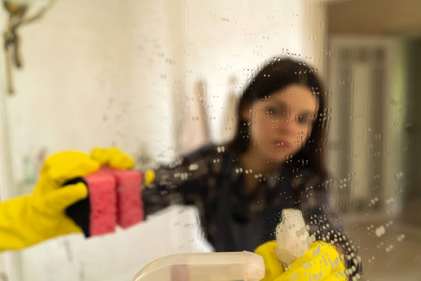 istock Young woman is washing mirror in the bathrom. 1359565709