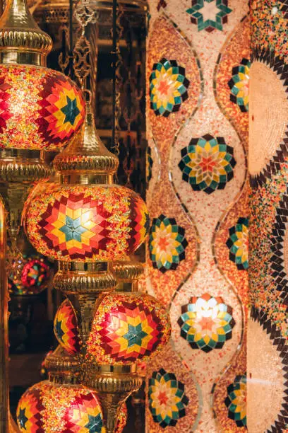 Photo of Vertical image with traditional turkish or moroccan light mosaic lamp. Colorful stained glass lamp against defocused souvenir shop background with copy space. Popular souvenir and ideas for present