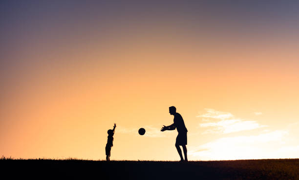 istock Father and son playing with a ball outdoors at sunset. 1359566040