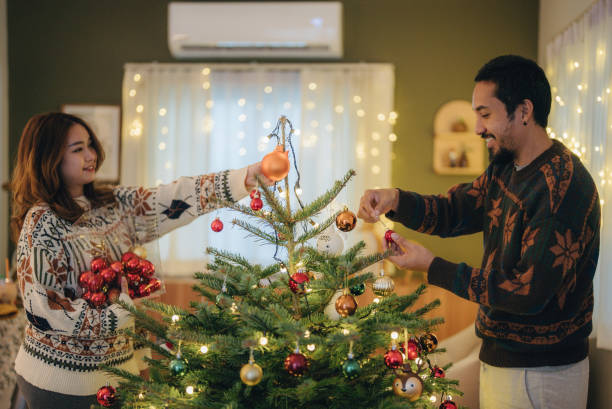 Happy young couple decorating Christmas tree stock photo