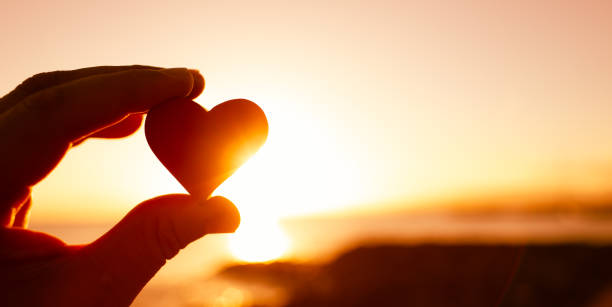 istock Hand holding heart against a sunset. 1359566189