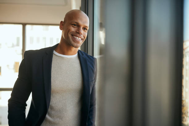 istock Happy black entrepreneur looking through the widow at his office. 1359569243
