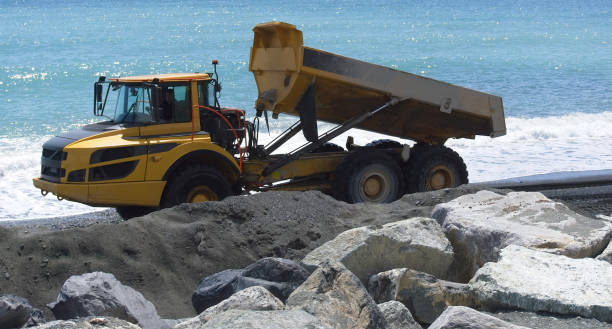 istock Industrial dumper trucks working on a construction in Genova city beach - Digging and moving sand with large dumper truck with sea in background 1359573911