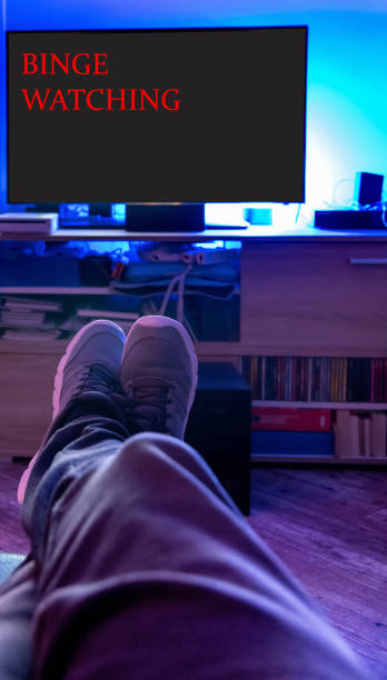 istock Man binge watching on the couch in a dark living room 1359576093