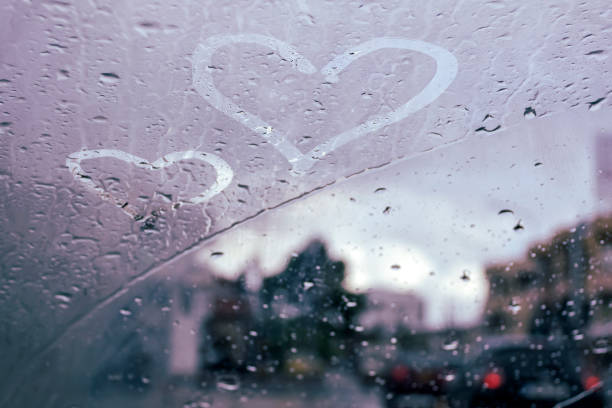 istock Wet car windshield with two heart drawings 1359577958
