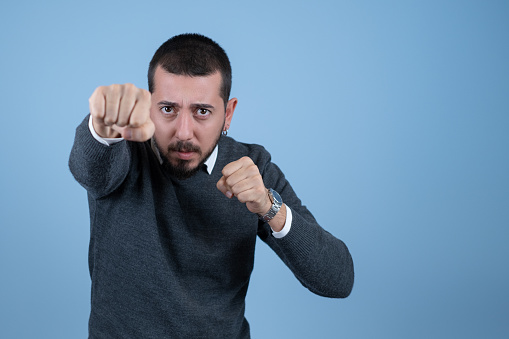 Stressed businessman punching in front of blue background