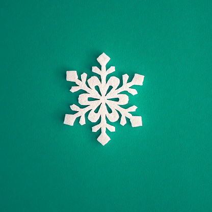 Christmas holidays composition, top view white snowflakes decoration on green and aquamarine background with copy space for text. Flat lay. Winter, postcard template.