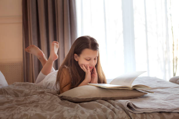 istock Girl lying on the bed and reading a book 1359583436