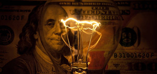 Rising electricity prices. Old light bulb and dollar bills stock photo