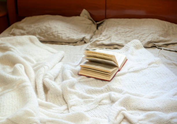 istock Opened book on a cozy white knit mohair blanket on a bed 1359584971