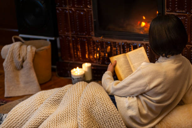 아늑한 분위기 있는 오두막 방에서 벽난로 근처에 누워 있는 갈색 머리 의 여자와 책을 읽고, 낮은 키 - blanket fireplace winter women 뉴스 사진 이미지