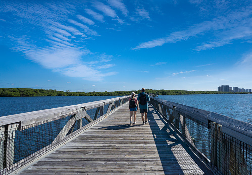 Father and daughter hiking on the pathway over the lake.MacArthur . Couple walking on the boardwalk in Florida. Beach State Park, North Palm Beach, Florida. USA.