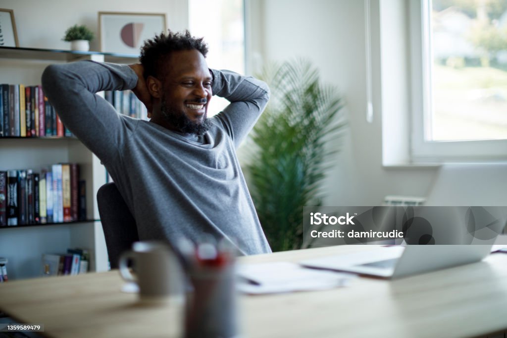 Happy mid adult man relaxing on a chair at home office Finishing Stock Photo