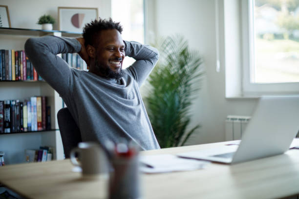 Happy mid adult man relaxing on a chair at home office stock photo