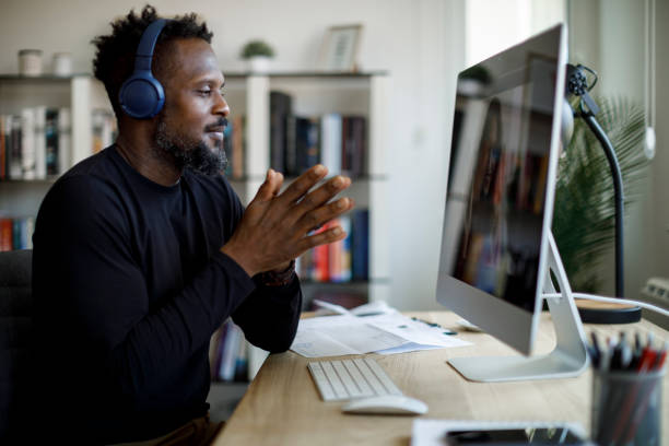 istock Smiling man with headphones having video call at home office 1359589612