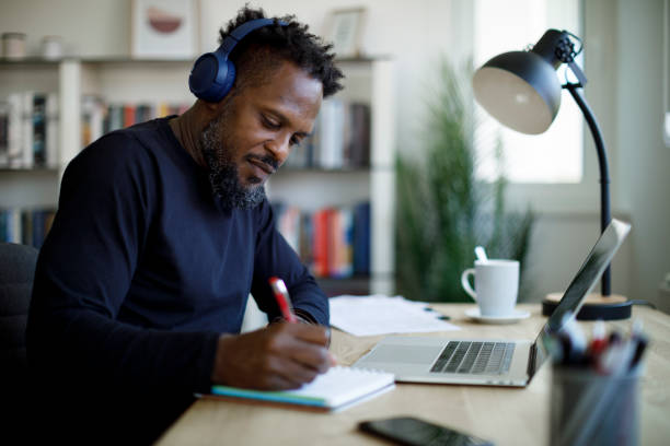 hombre con auriculares bluetooth trabajando en la oficina en casa - only men mid adult men men author fotografías e imágenes de stock