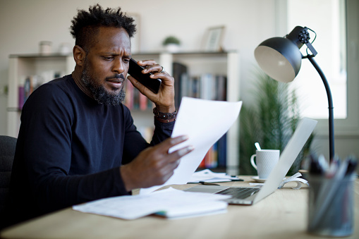 Worried man talking on the phone while working from home