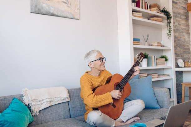 istock Happy senior woman learning to play guitar 1359591879