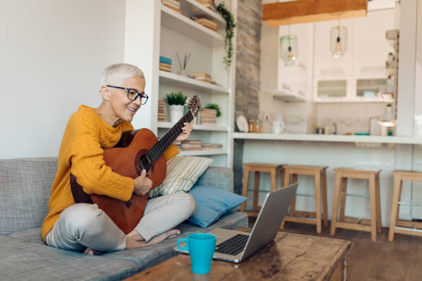 istock Senior woman using an online tutorial to learn to play guitar 1359591881