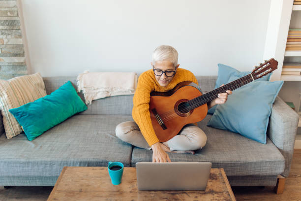 istock Senior woman practicing playing acoustic guitar 1359591885