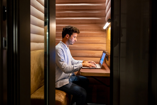 Focused business man working in an isolated booth at the office using a laptop computer