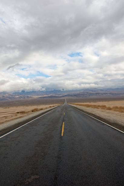 istock Long straight road across valley floor with scud cloud cover 1359594514