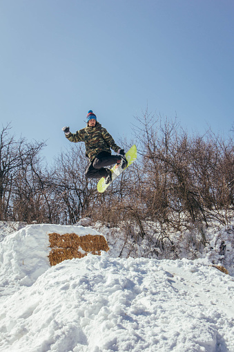 A young man suspended in mid-air making snowboard jump