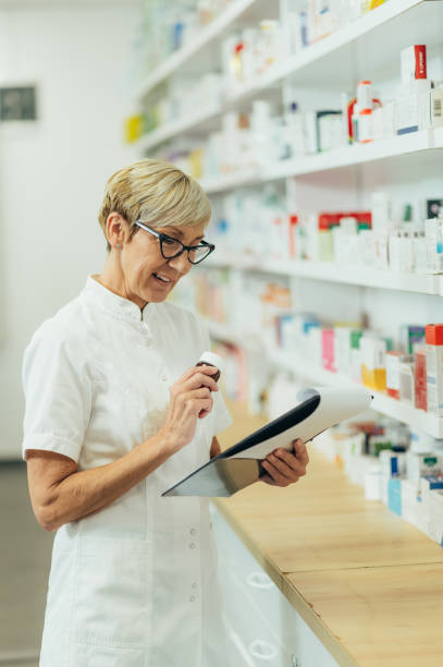 istock Beautiful senior female pharmacist checking medications on a shelf 1359597417