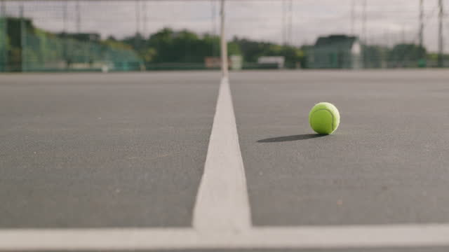 4k video footage of a ball bouncing on a dividing line in an empty tennis outside