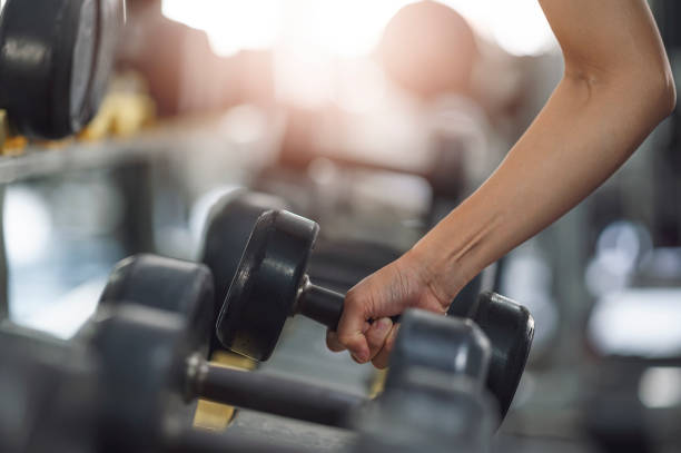 istock Close-up female hands lifting dumbbells at gym. 1359613984