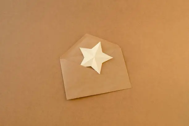 White paper star in an envelope made brown kraft paper. Asterisk in envelope. Letter with paper star
