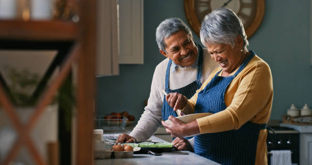 scatto di una coppia anziana felice che cuoce a casa - 60 anni foto e immagini stock